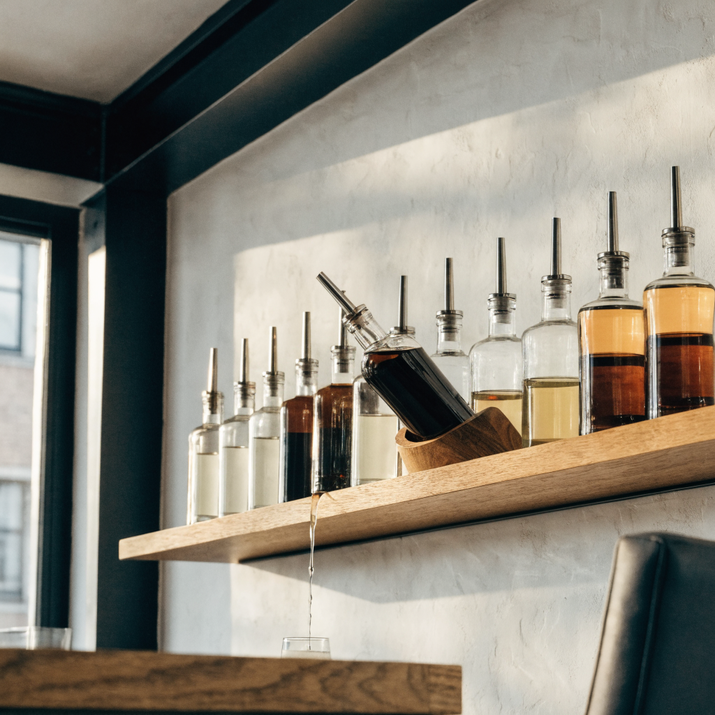 Flessen met freeflow schenktuiten op een houten flessenplank - Glazen.nl