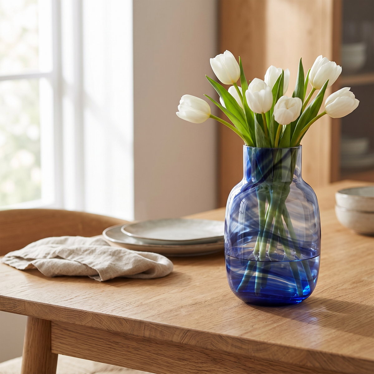 Blauwe Waters vaas met witte tulpen op een eikenhouten tafel